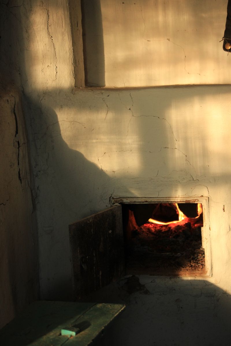Warm glow of a traditional brick oven with shadows on the wall, evoking rustic charm.